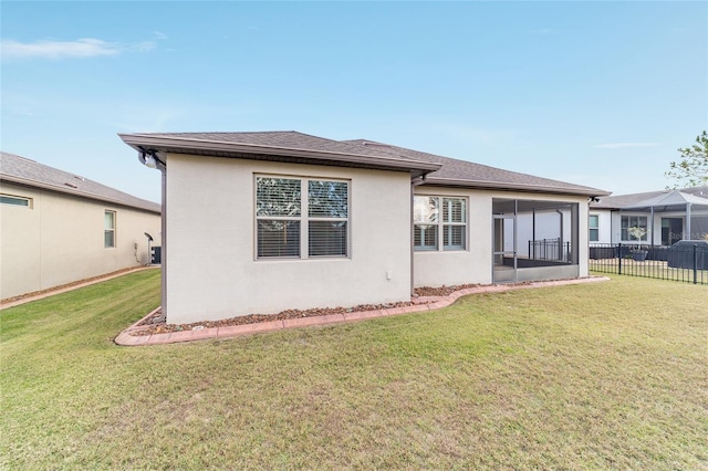 rear view of house featuring a sunroom and a yard