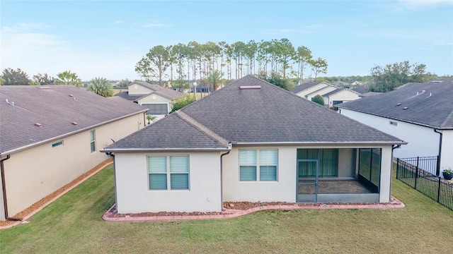 rear view of house with a sunroom and a lawn