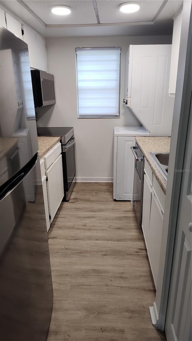 kitchen featuring light hardwood / wood-style flooring, white cabinets, stainless steel appliances, and sink