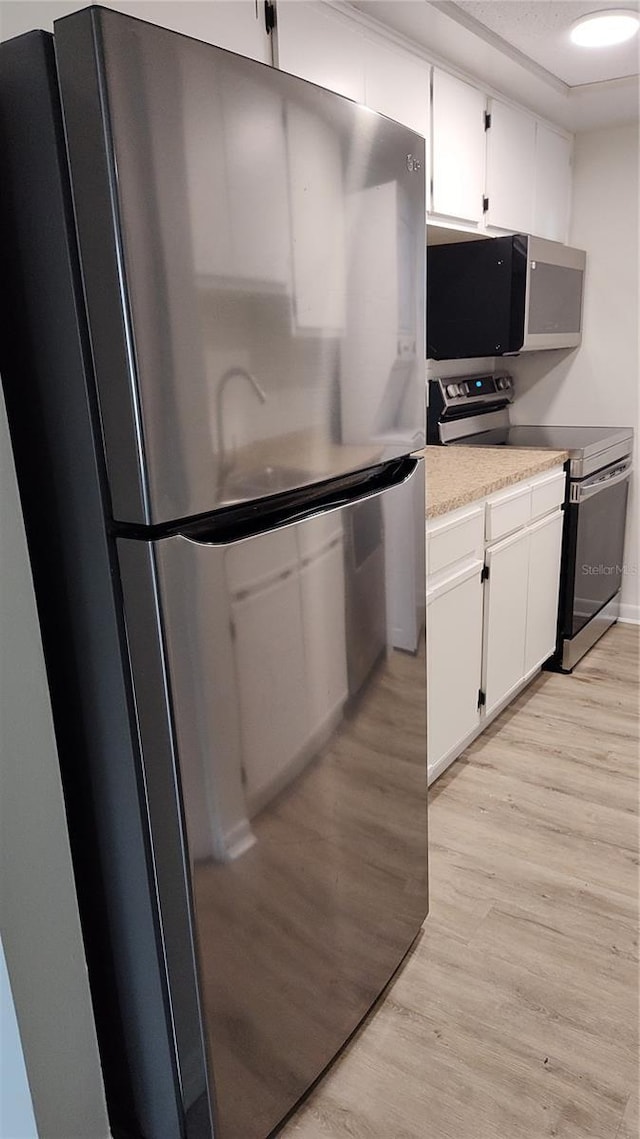 kitchen with white cabinetry, stainless steel appliances, and light hardwood / wood-style floors