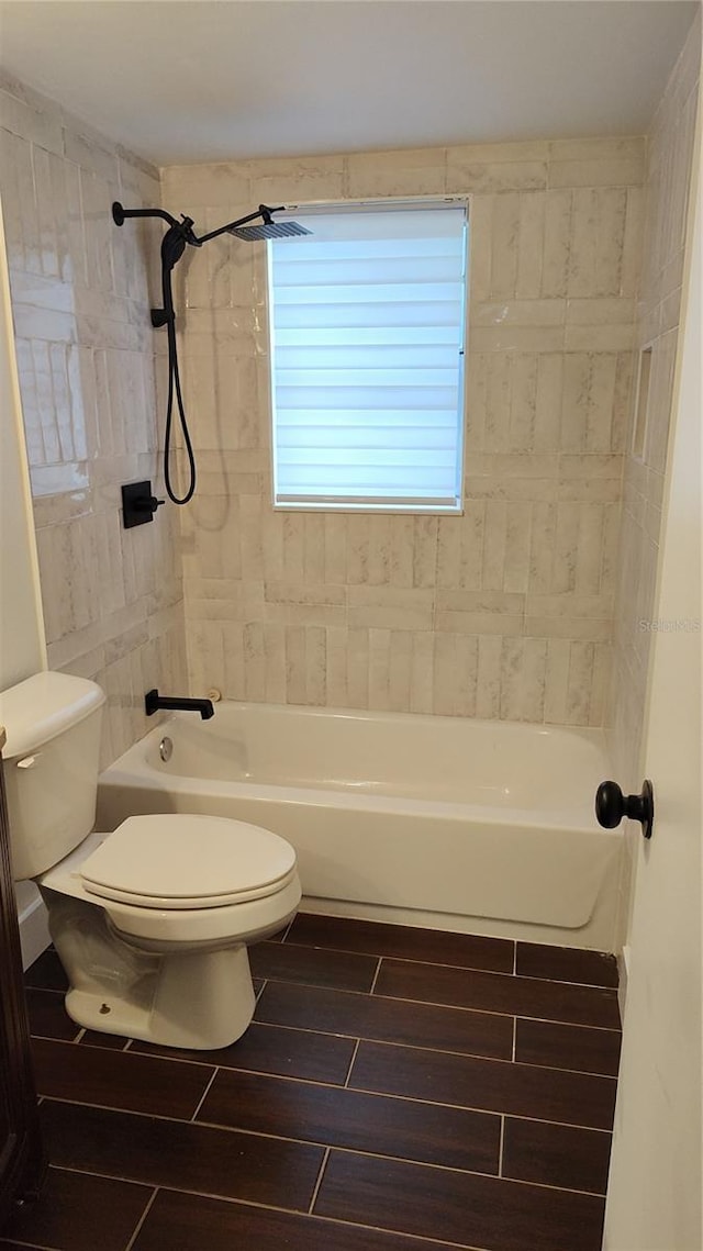 bathroom featuring tiled shower / bath combo and toilet