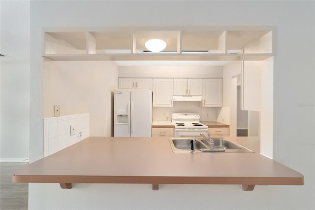 kitchen with sink, tasteful backsplash, kitchen peninsula, white appliances, and a breakfast bar area