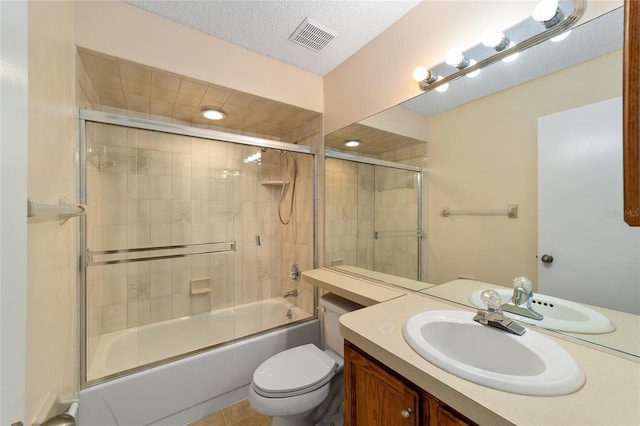 full bathroom featuring vanity, combined bath / shower with glass door, tile patterned flooring, toilet, and a textured ceiling