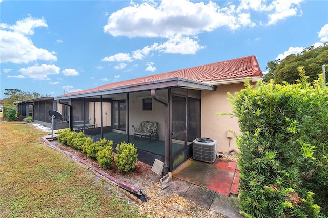 back of property featuring a lawn, a sunroom, and central AC unit