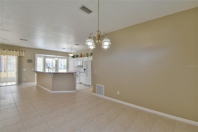 kitchen featuring white appliances, light tile patterned floors, decorative light fixtures, a center island, and white cabinetry