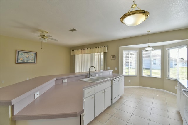 kitchen with white dishwasher, sink, light tile patterned floors, decorative light fixtures, and white cabinets