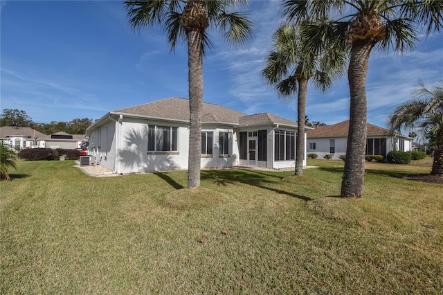 rear view of property featuring a lawn, a sunroom, and cooling unit