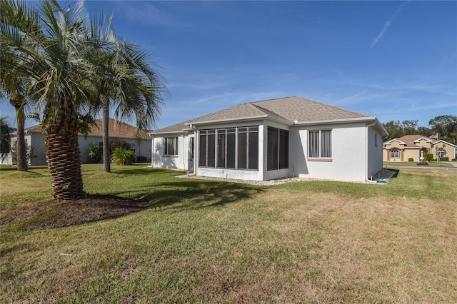 back of house featuring a sunroom and a lawn