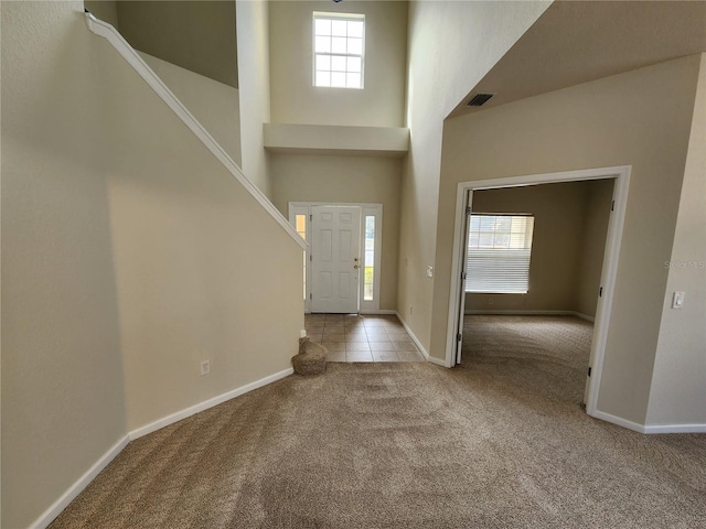 carpeted entrance foyer featuring a towering ceiling