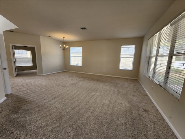 unfurnished room featuring a chandelier, carpet floors, and a healthy amount of sunlight