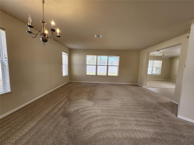 empty room with carpet, ceiling fan with notable chandelier, and plenty of natural light