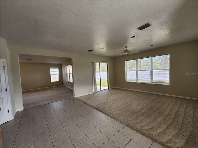 tiled spare room with ceiling fan, a healthy amount of sunlight, and a textured ceiling