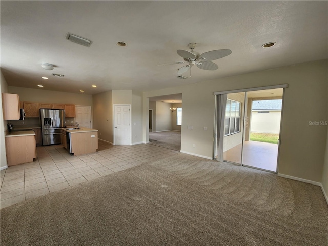 unfurnished living room with ceiling fan, sink, and light colored carpet