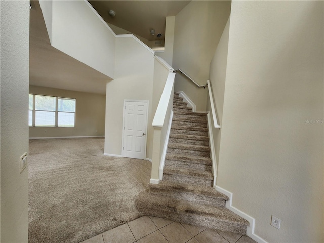 stairs with tile patterned floors and a towering ceiling