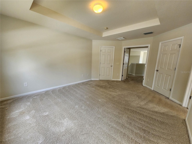 unfurnished room featuring a tray ceiling and carpet flooring