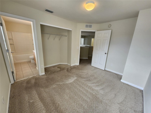 unfurnished bedroom featuring ensuite bath, carpet floors, and a closet