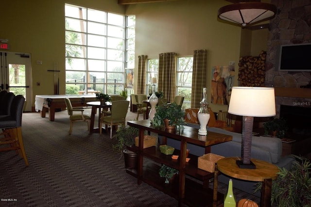 carpeted dining area with a towering ceiling, a wealth of natural light, and pool table