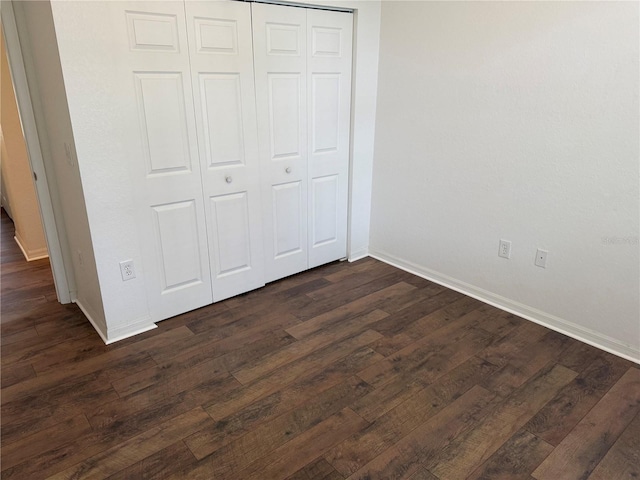 unfurnished bedroom featuring dark hardwood / wood-style flooring and a closet