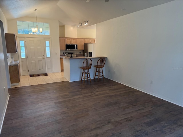 entrance foyer featuring a chandelier, a textured ceiling, vaulted ceiling, and light hardwood / wood-style flooring