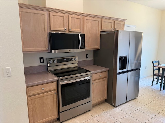 kitchen with light tile patterned flooring, stainless steel appliances, and light brown cabinets