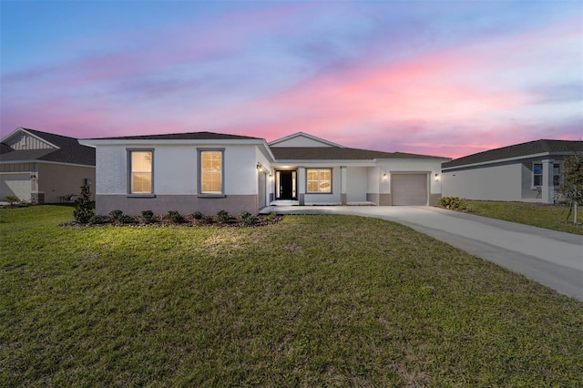 ranch-style home featuring a garage and a lawn