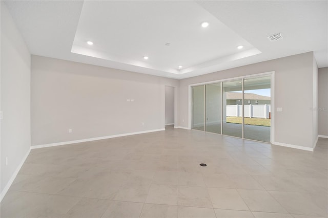 empty room featuring light tile patterned floors and a raised ceiling