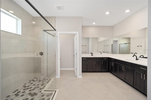 bathroom featuring tile patterned flooring, a tile shower, and vanity