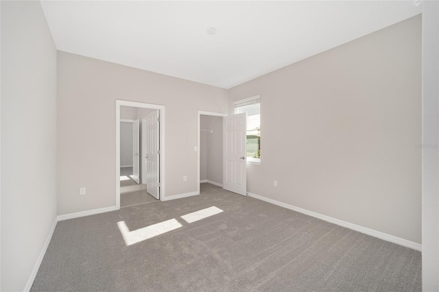 unfurnished bedroom featuring a spacious closet, carpet floors, and ensuite bath