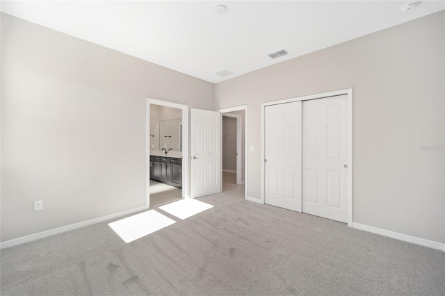 unfurnished bedroom with light colored carpet, sink, and a closet