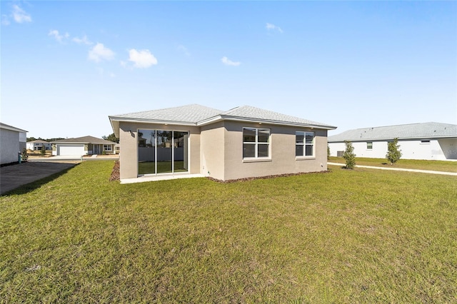 rear view of property featuring a lawn and a garage