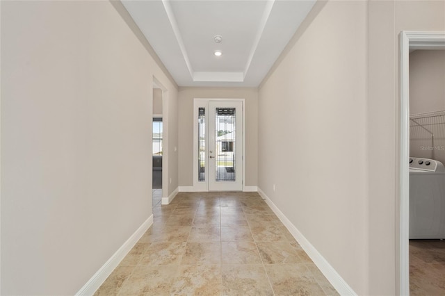 interior space with a raised ceiling, washer / clothes dryer, and french doors