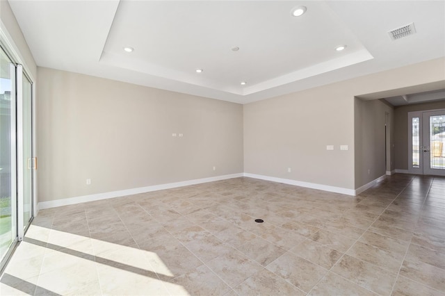 empty room with french doors and a tray ceiling