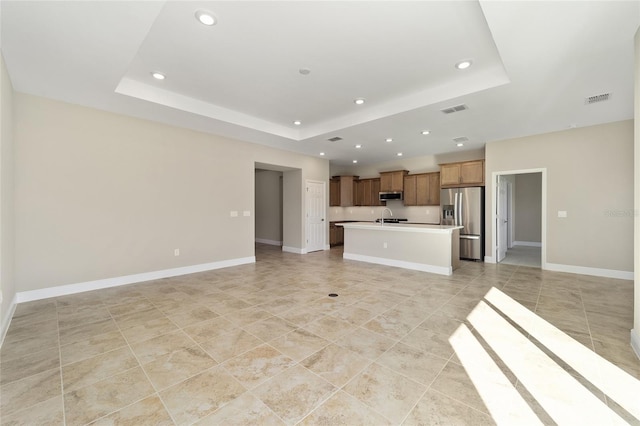 unfurnished living room featuring a tray ceiling and sink