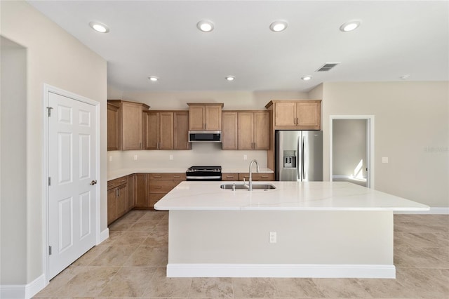 kitchen with light stone countertops, stainless steel appliances, sink, range hood, and an island with sink