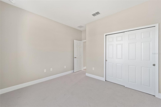 unfurnished bedroom featuring light colored carpet and a closet