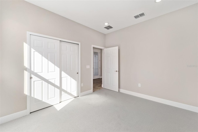 unfurnished bedroom featuring a closet and light colored carpet