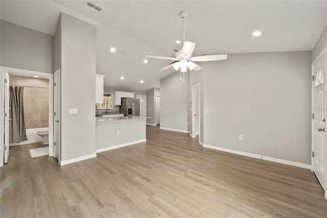 unfurnished living room featuring high vaulted ceiling, light hardwood / wood-style flooring, and ceiling fan