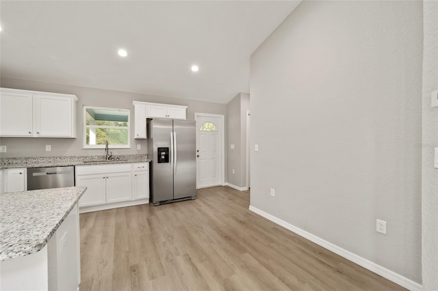 kitchen with sink, vaulted ceiling, light hardwood / wood-style flooring, white cabinetry, and stainless steel appliances