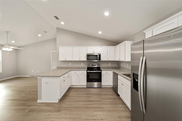 kitchen with white cabinets, kitchen peninsula, appliances with stainless steel finishes, and vaulted ceiling