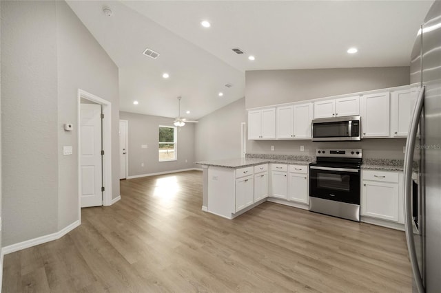 kitchen with light stone counters, light hardwood / wood-style flooring, lofted ceiling, white cabinets, and appliances with stainless steel finishes