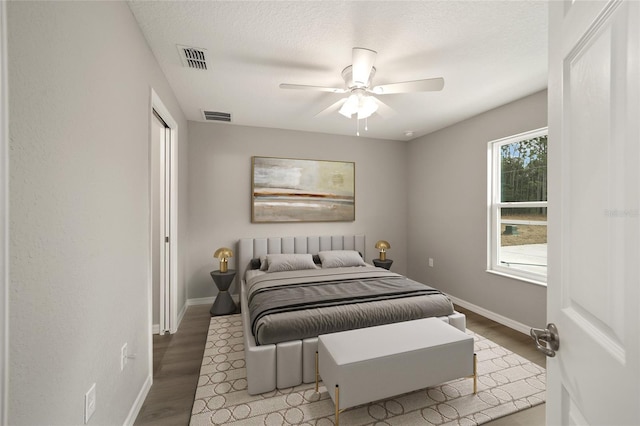 bedroom with hardwood / wood-style floors, ceiling fan, and a textured ceiling