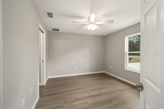 spare room with hardwood / wood-style floors, ceiling fan, and a textured ceiling