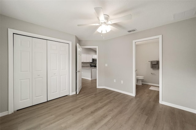 unfurnished bedroom with ceiling fan, a closet, connected bathroom, and light hardwood / wood-style flooring