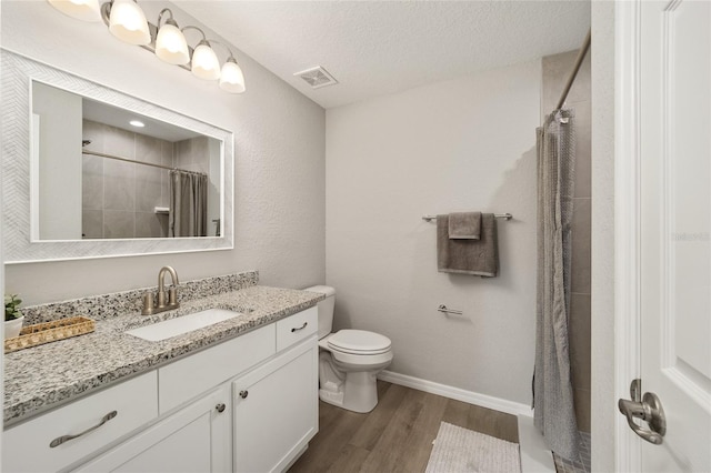 bathroom featuring a shower with shower curtain, vanity, a textured ceiling, hardwood / wood-style floors, and toilet