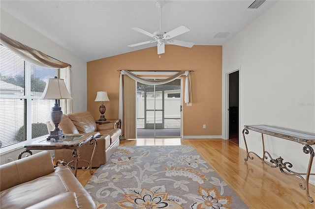 living room featuring light hardwood / wood-style floors, vaulted ceiling, ceiling fan, and a textured ceiling