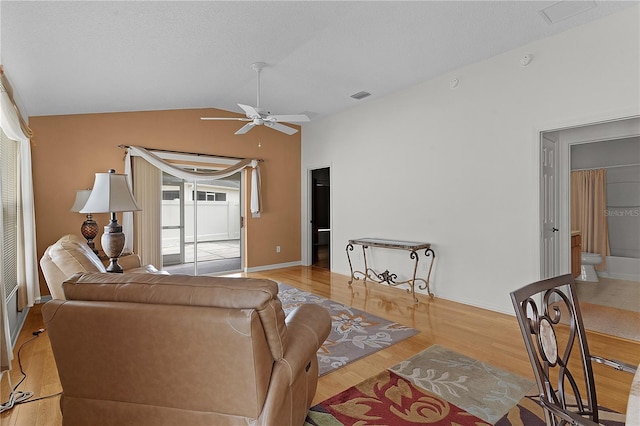 living room featuring light wood-type flooring, lofted ceiling, a textured ceiling, and ceiling fan