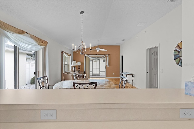 dining space with a textured ceiling, vaulted ceiling, and an inviting chandelier