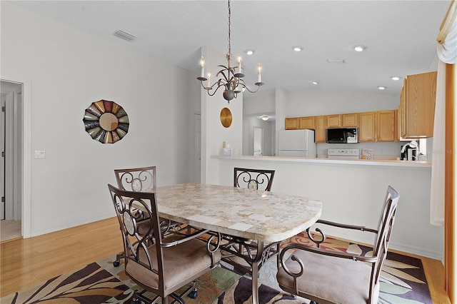 dining area featuring an inviting chandelier, light wood-type flooring, vaulted ceiling, and sink