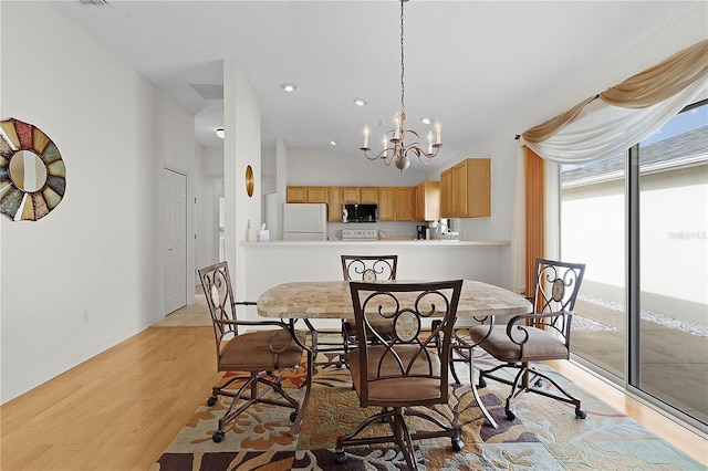 dining room featuring light wood-type flooring, an inviting chandelier, and vaulted ceiling