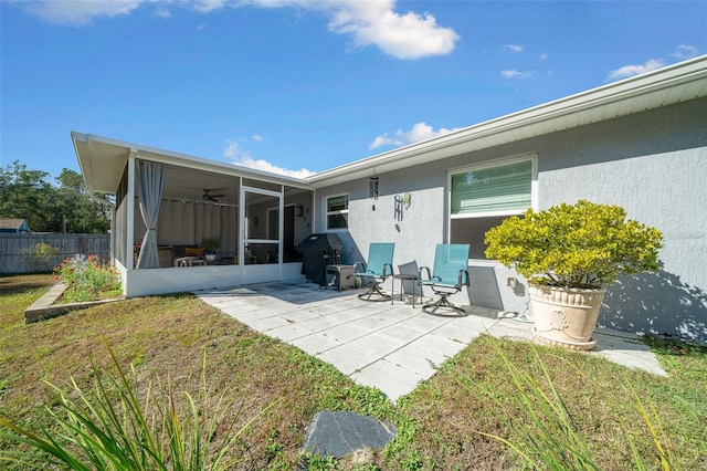 back of property featuring a lawn, a sunroom, and a patio